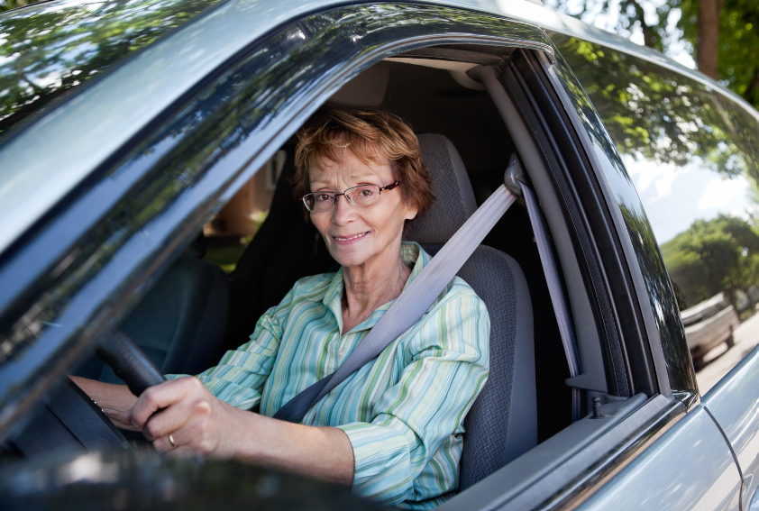 femme âgé souriante qui conduit une voiture